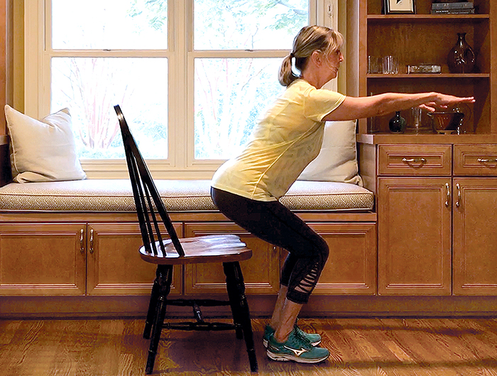 woman doing squat with chair