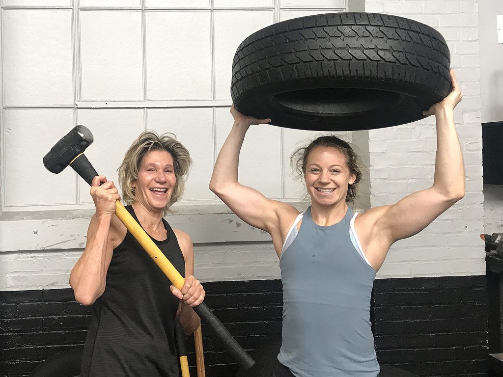 women exercising with sledgehammer and tires