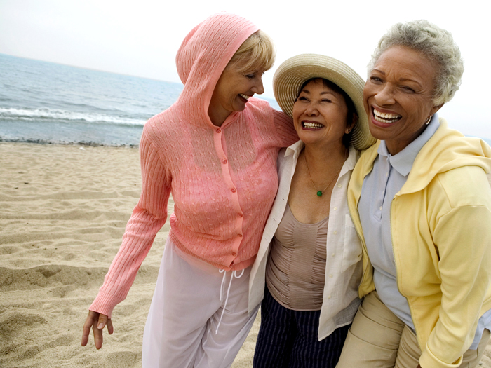 three women laughing together on a beach
