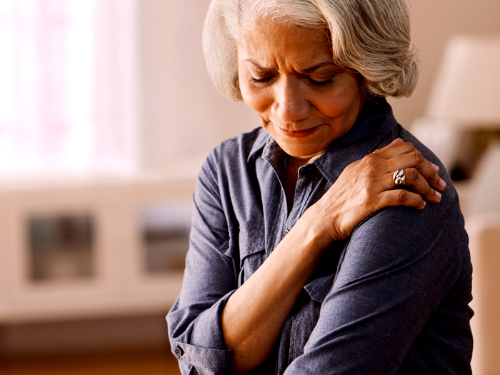 older woman holding her shoulder