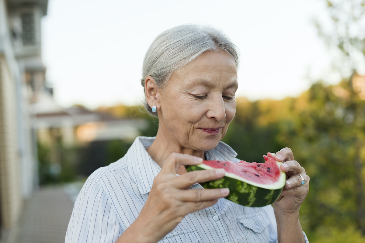 Senior woman eating watermelon in the garden