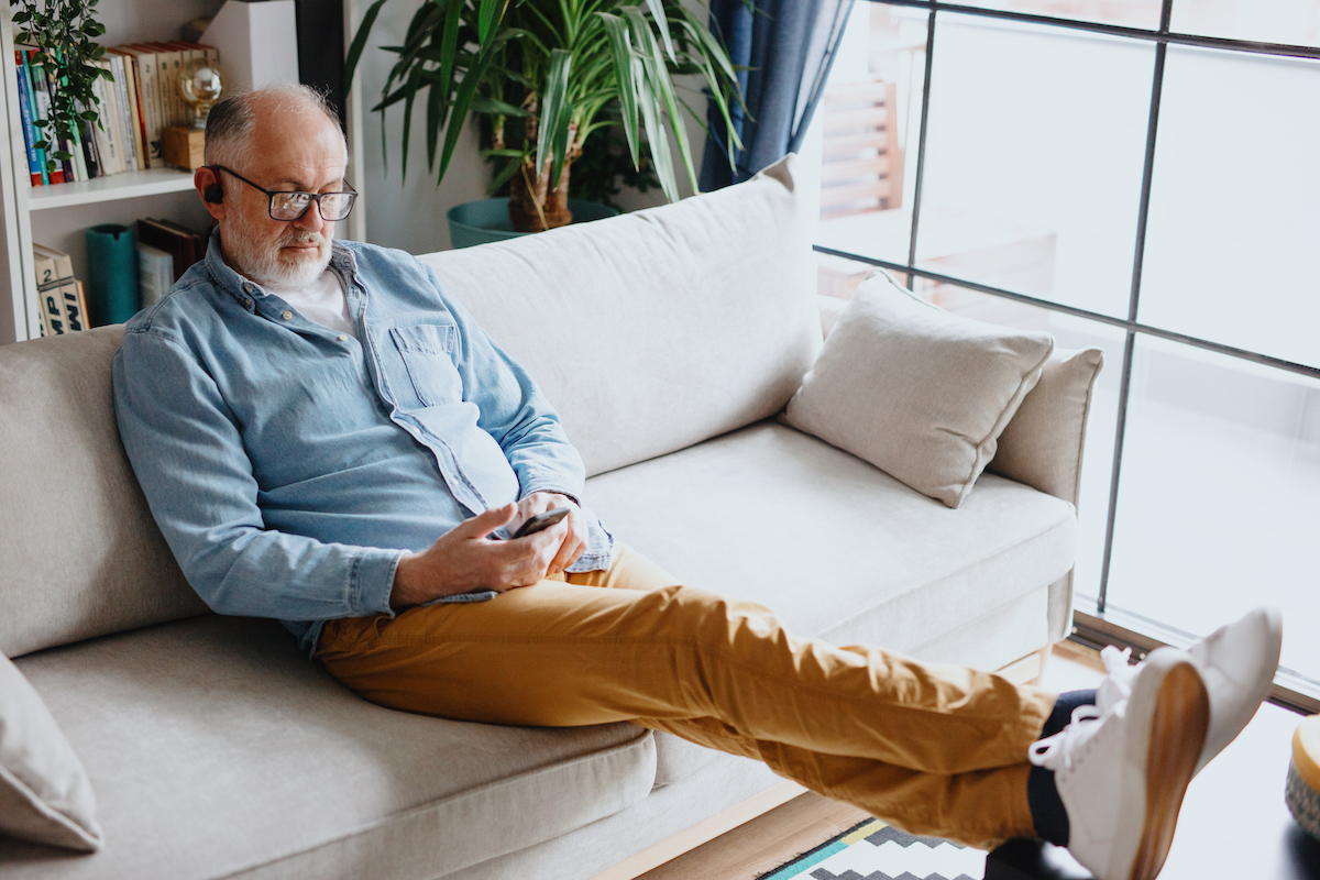 Senior man listening to smartphone at home