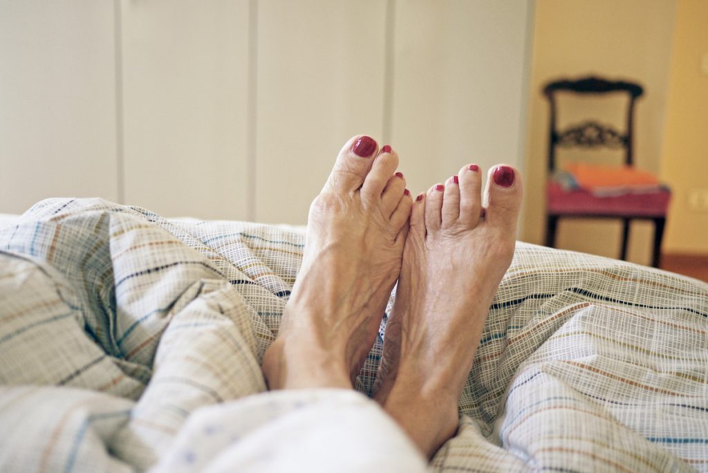 Older woman's bare feet on bed