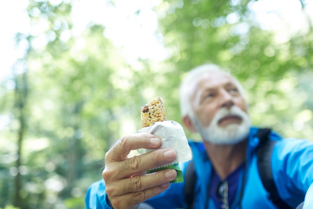 active senior hiker eating protein snack bar