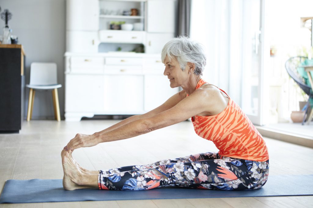 fit senior woman stretching her legs and back